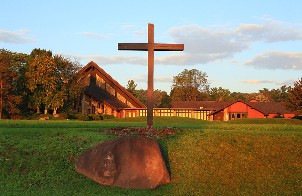 front exterior of Genesee Abbey church, with wooden cross in front