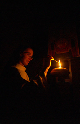 nun lighting oil lamp in a dark space