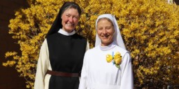 Sr. Sharon and Mother Vicky smiling in front of yellow bush