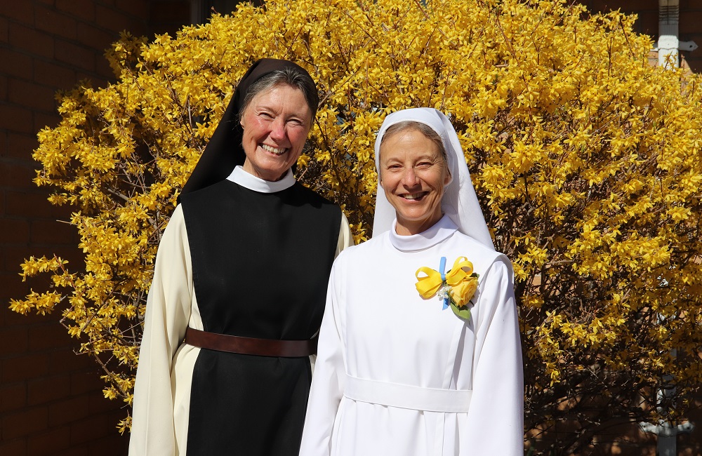 Sr. Sharon and Mother Vicky smiling in front of yellow bush