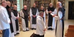 Br. Paul enters Holy Cross Abbey as a Postulant, kneeling surrounded by fellow monks