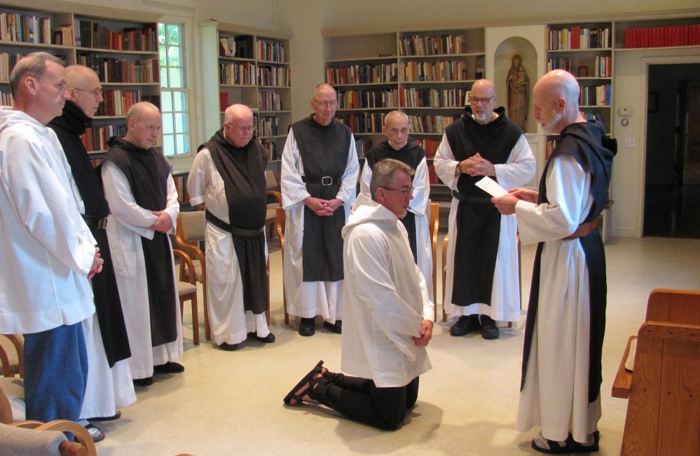 Br. Paul enters Holy Cross Abbey as a Postulant, kneeling surrounded by fellow monks