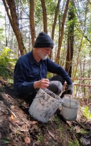 Fr. Casey at Redwoods Abbey, with buckets on side of forest slope