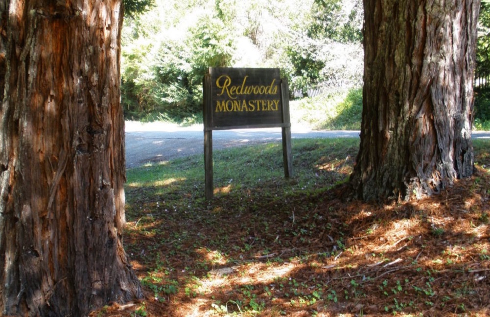 Redwoods Monastery sign between large redwoods trees
