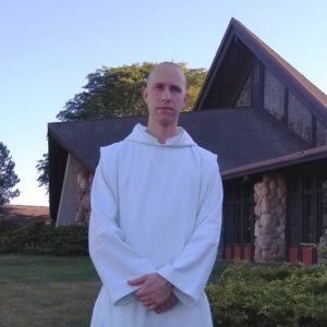 Br. Placid, monk in white habit standing in front of Genesee Abbey Church