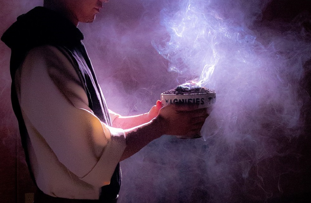 monk holding bowl of smoking incense