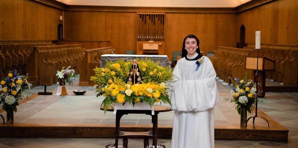 Sr Karla in new cowl smiles in front of the altar