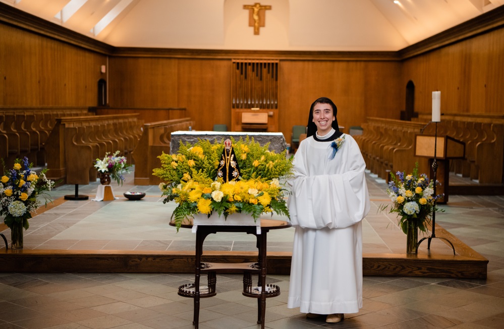 Sr Karla in new cowl smiles in front of the altar