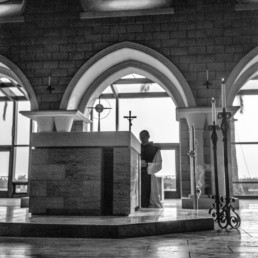 Black and White image of monk worshiping Blessed Sacrament on altar of ancient Church