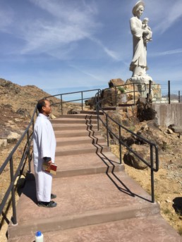 A monk in the desert on stairway leading to stature of Our Lady of LaVang