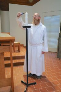 Br. Clement, novice monk at Mepkin Abbey, lights a candle in the Abbey Church