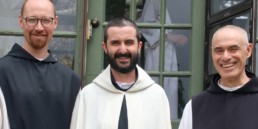 Br. Kenneth smiling between two other monks