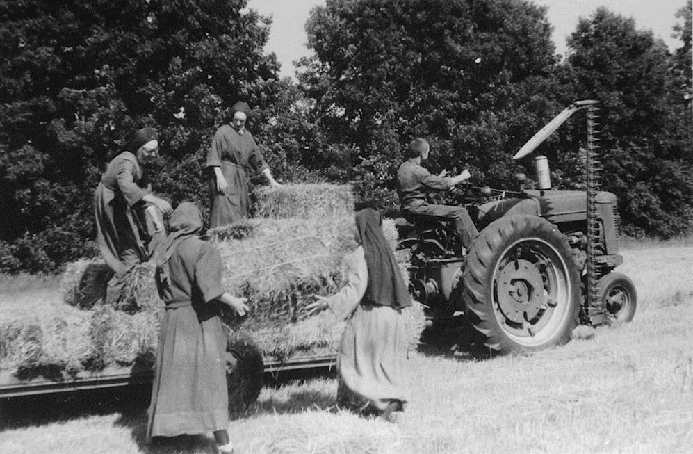 old black and white photo of several Wrentham sister loading hay into a wagon