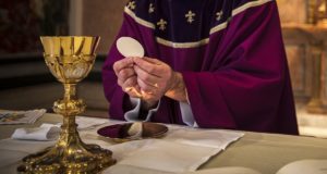 Priest at altar with host and chalice