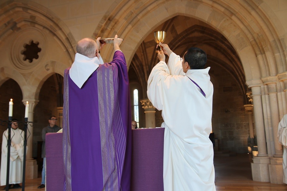 Priests at altar elevating paten and chalice