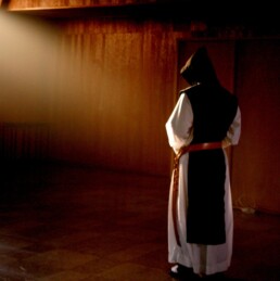 A Trappist monk standing in a beam of light, contemplating God