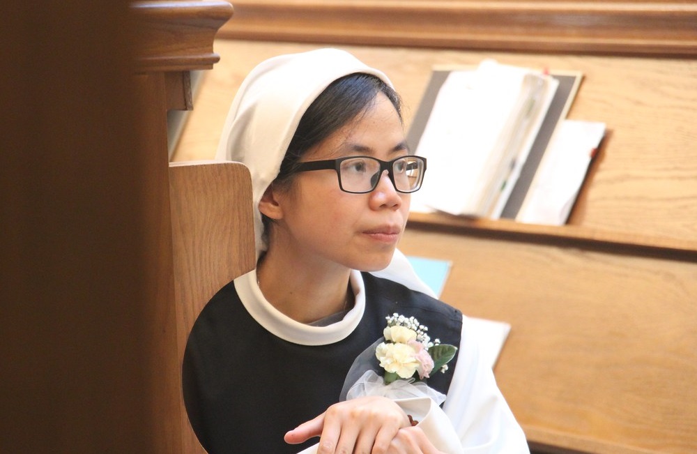 Sister Thao, a Trappistine nun, kneels in choir stall.